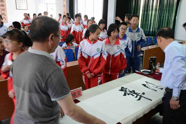 (中国书法家协会会员苟成文现场为学生示范书法技艺)(学生们观看非遗